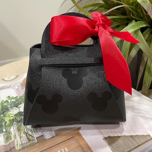 May include: A black handbag with a red bow and Mickey Mouse silhouettes. The bag has a top handle.