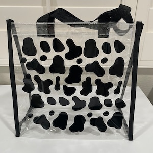 May include: Clear plastic tote bag with black cow print design and black handles.