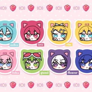 May include: A set of eight circular stickers featuring chibi-style characters wearing cat-ear hoods. The characters are labeled Miku, Teto, Rin, Len, Luka, Gumi, Flower, and Kaito. The background is light pink with a repeating pattern of strawberries.