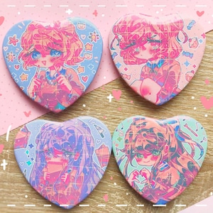 May include: Four heart-shaped buttons featuring anime-style illustrations of girls. Each button has a different girl with pink, blue, and purple color schemes. The buttons have a glossy finish and are set against a pink and white background.