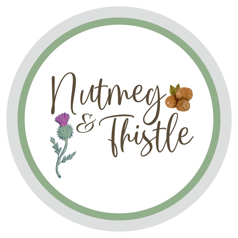 Pu&ograve; includere: Un cerchio bianco con un bordo verde e grigio. Il testo "Nutmeg & Thistle" &egrave; scritto in corsivo marrone. Un cardo viola e noci moscate marroni sono illustrate su entrambi i lati del testo.