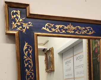 May include: A gold and blue mirror with a decorative ornate frame. The frame has a blue background with gold leaf accents and a floral design.
