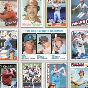 May include: A collection of vintage baseball cards featuring Mike Schmidt of the Philadelphia Phillies. The cards display action shots, portraits, and team logos, with text including "Phillies" and "1973 Rookie Third Basemen."