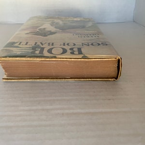 May include: A vintage hardcover book titled "Bob, Son of Battle" by Alfred Ollivant. The book cover features a black and white illustration of a dog.