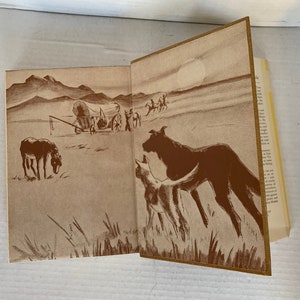 May include: A sepia-toned illustration of a covered wagon travelling across a vast, open plain. Two dogs, one large and one small, are in the foreground, looking towards the wagon. The sun is shining brightly in the sky.