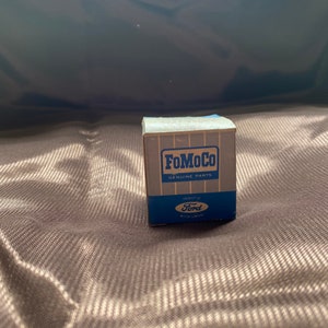 May include: A small cardboard box with blue and white text that reads "FoMoCo Genuine Parts" and "Ford" with a blue and white logo.