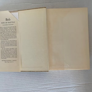 May include: A vintage book titled "Bob, Son of Battle" by Alfred Ollivant. The book cover features a brown and green illustration of a dog in a forest setting. The book is published by Grosset & Dunlap, New York 13, N.Y.