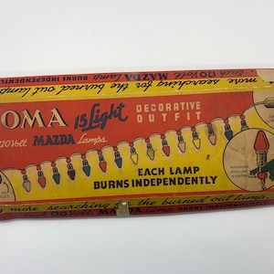 Puede incluir: Una caja vintage de luces navideñas decorativas Noma de 15 luces con lámparas Mazda de 120 voltios. La caja es roja, amarilla y blanca con una ilustración de las luces enhebradas en un árbol. El texto en la caja dice "Noma 15 Light Decorative Outfit with 120 Volt Mazda Lamps. Each Lamp Burns Independently."