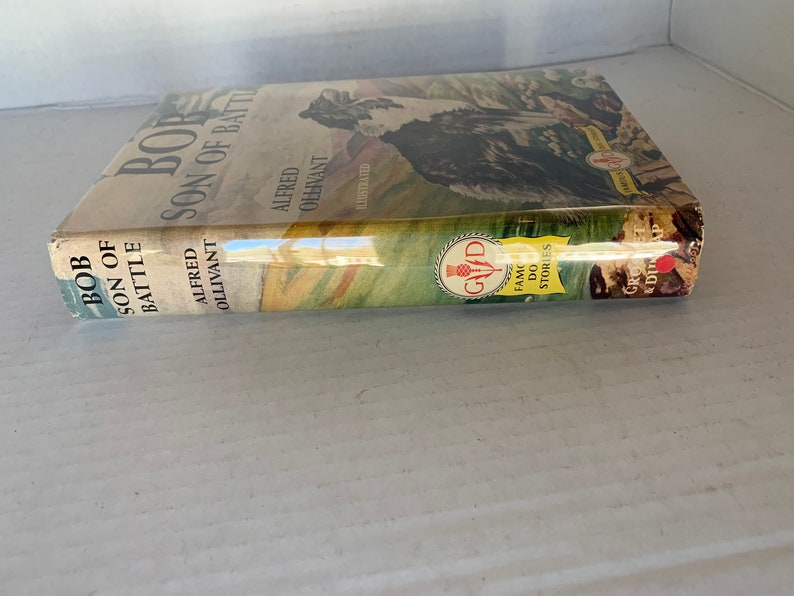 May include: A vintage book cover with a brown and white dog on the front. The title is "Bob, Son of Battle" by Alfred Ollivant. The book is part of the "Famous Dog Stories" series.