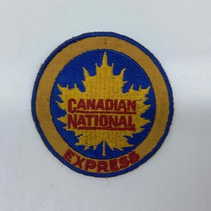 May include: A round, embroidered patch with a yellow maple leaf on a blue background. The words "Canadian National Express" are in red and yellow lettering.