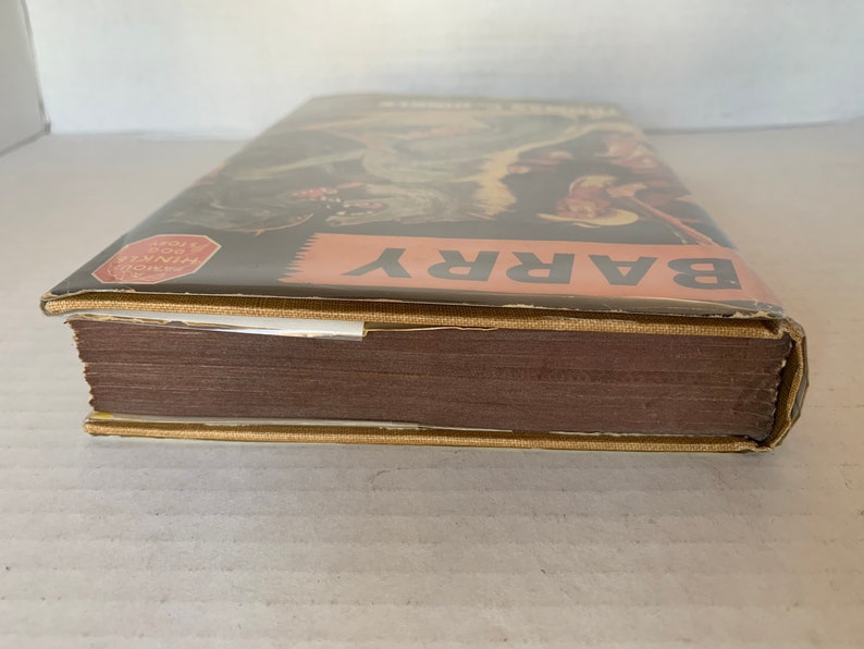 May include: A brown hardback book with a gold spine and a dust jacket. The dust jacket features a colourful illustration of a cowboy riding a horse. The text "BARRY" is printed in large white letters on the dust jacket. The text "HISTORY OF THE WORLD" is printed in red on a white circle on the dust jacket.