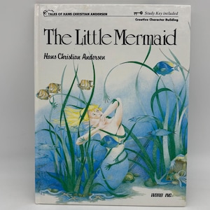 May include: A book cover featuring an illustration of a mermaid with long blonde hair swimming in a blue and green underwater scene. The title of the book is "The Little Mermaid" by Hans Christian Andersen.