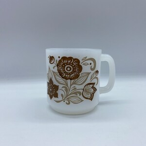 Peut inclure: Une tasse en céramique blanche avec un motif floral brun. La tasse a une anse et est parfaite pour le café ou le thé.