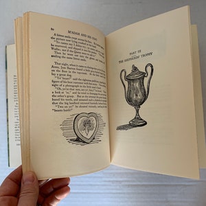 May include: A book open to a page with text about a dog and a trophy. The text reads "Madam and His Coat" and "The Shepherd's Trophy". There is a black and white illustration of a dog and a trophy.