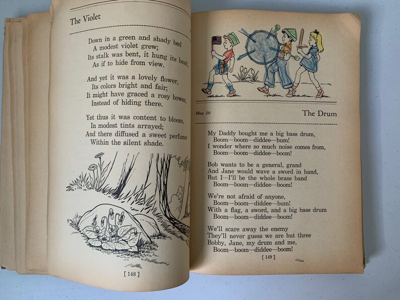 Puede incluir: Un libro infantil vintage con ilustraciones de una flor de violeta y ni&ntilde;os jugando con un tambor. El texto en la p&aacute;gina dice "The Violet" y "The Drum".