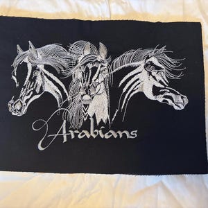 Può includere: Toppa ricamata nera con tre teste di cavalli arabi bianchi. La parola "Arabians" è ricamata in corsivo sotto i cavalli. La toppa è rettangolare.