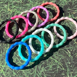 May include: A set of 10 silicone rings in various pastel colors, including pink, blue, green, and white. The rings are all the same size and have a wavy texture.