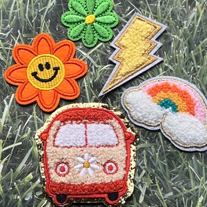 May include: Five colorful iron-on patches with a retro 70s theme. The patches include a smiling flower, a lightning bolt, a rainbow, a daisy, and a vintage van.
