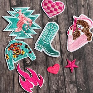 May include: A set of nine embroidered iron-on patches featuring a cowboy boot, a heart, a star, a flame, a jacket, a cowgirl, and a geometric design. The patches are all pink, green, and white.