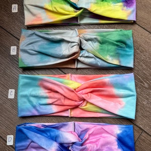 May include: Four tie-dye headbands in different color combinations. The headbands are made of a soft, stretchy fabric and have a knotted design. The colors include blue, green, yellow, pink, and orange.