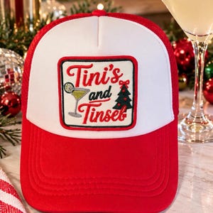 May include: A red and white trucker hat featuring a rectangular patch with the text Tini's and Tinsel, an embroidered martini glass with a lime slice, and a green Christmas tree with a red bow on top.