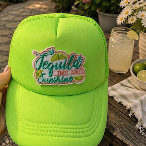 Puede incluir: Gorra de camionero verde neón con parte trasera de malla. La gorra presenta un parche bordado con las palabras "Tequila, Lime and Sunshine". Un accesorio brillante y veraniego.