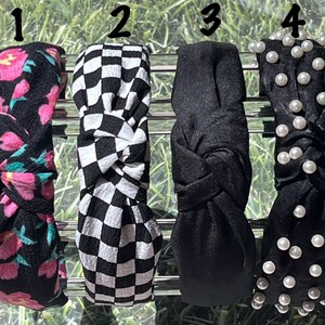 May include: Four different headbands with various patterns. The first headband is black with pink and blue floral print. The second headband is black and white checkered. The third headband is black with a knotted design. The fourth headband is black with white pearl embellishments.