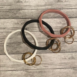 May include: Three silicone key rings in black, white, and pink. Each ring has a gold metal key chain attached.