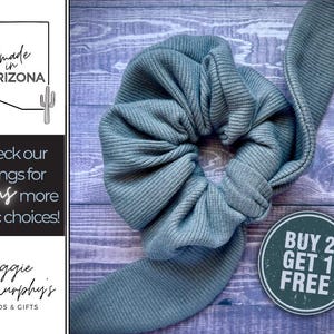 May include: A blue ribbed fabric scrunchie with a "BUY 2 GET 1 FREE" sign. The scrunchie is handmade in Arizona.