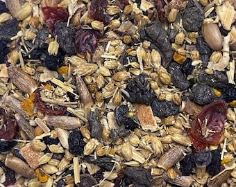 May include: Close-up of a mix of dried herbs and spices. The blend includes dark berries, seeds, and various plant parts in shades of brown, red, and yellow. The texture is varied, with some pieces appearing whole and others fragmented.