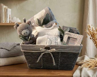 May include: A dark gray woven basket containing a crocheted animal toy, a white knit baby garment, and a small white picture frame with polka dots. The basket is tied with a light gray ribbon and holds a soft gray blanket folded in the back.