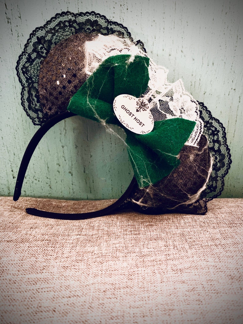 May include: Black headband with a green bow and black and white lace. The bow has a white tag that says "Ghost Host".