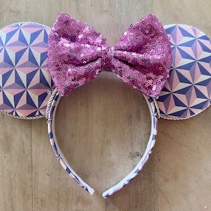 May include: Purple and blue geometric patterned Minnie Mouse ears with a pink sequined bow.