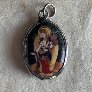 May include: Silver oval pendant with a colorful image of a woman holding a lotus flower.