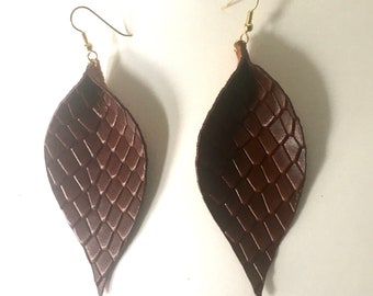 May include: A pair of brown leather earrings with a snake skin pattern. The earrings are dangle style with gold hooks.