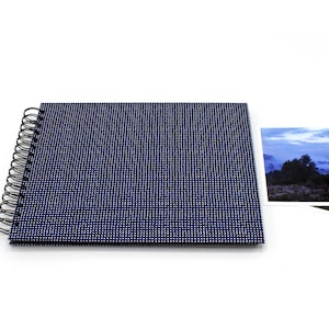 May include: A blue spiral-bound photo album with a textured cover and two landscape photographs. The album cover features a pattern of small white dots. The photographs depict a scenic view.