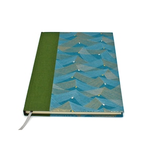 Può includere: Un taccuino con copertina rigida, dorso in tessuto verde oliva a tinta unita e copertina anteriore decorata con un motivo ripetitivo di onde blu. Il disegno è composto da sottili linee chiare che formano onde geometriche con piccoli accenti gialli.
