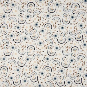 Op de afbeelding: Een witte stof met een herhalend patroon van gestileerde blauwe en bruine bloemen. De bloemen zijn gemaakt van kleine cirkels en halve cirkels.