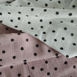 Puede incluir: Dos piezas de tela con lunares negros. Una pieza es blanca y la otra rosa.