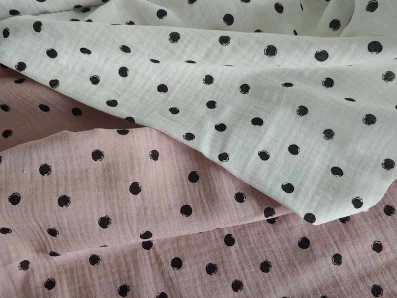 Puede incluir: Dos piezas de tela con lunares negros. Una pieza es blanca y la otra rosa.