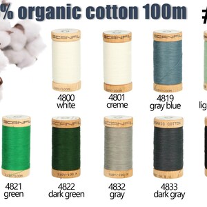 K&ouml;nnte beinhalten: Zehn Garnrollen aus 100% Bio-Baumwolle von Scanfil mit jeweils 100m L&auml;nge in verschiedenen Farben wie Wei&szlig;, Creme, Graublau, Hellgr&uuml;n, Gr&uuml;n, Dunkelgr&uuml;n, Grau, Dunkelgrau und Schwarz, erg&auml;nzt durch Baumwollbl&uuml;ten in der Ecke.