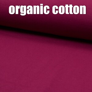 May include: A close-up of a deep burgundy fabric with the text "organic cotton" printed on it.