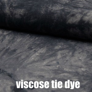May include: Close-up of a dark grey fabric with a tie-dye pattern. The fabric is made of viscose.