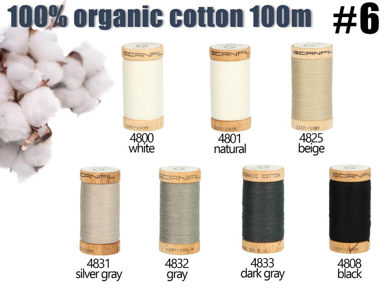 K&ouml;nnte beinhalten: Sieben Garnrollen aus 100% Bio-Baumwolle, jeweils 100m lang, mit der Aufschrift Scanfil. Die Farben umfassen Wei&szlig;, Natur, Beige, Silbergrau, Grau, Dunkelgrau und Schwarz. Jede Holzspule zeigt eine Farbnummer und den Namen darunter.
