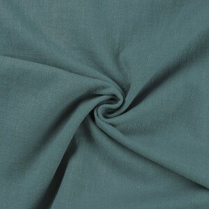 May include: A close-up of a soft, teal fabric with a textured surface. The fabric is folded and draped, creating a smooth, flowing look.