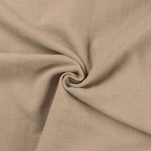 May include: A close-up of a beige fabric with a textured surface. The fabric is folded and draped, creating a soft and inviting look.