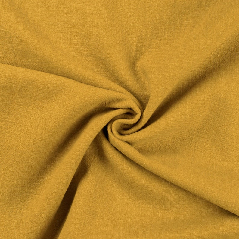 May include: A close-up of a mustard yellow fabric with a textured surface. The fabric is folded and draped, creating a soft and inviting look.