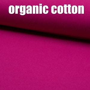 Könnte beinhalten: Nahaufnahme eines leuchtend magentafarbenen Stoffes mit dem aufgedruckten Text "organic cotton".