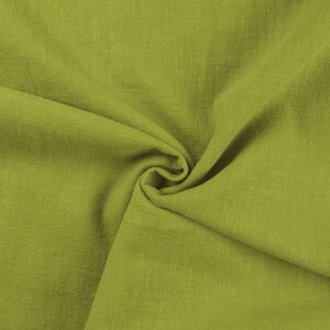 May include: A close-up of a soft, green fabric with a textured surface. The fabric is folded and draped, creating a smooth, flowing look.