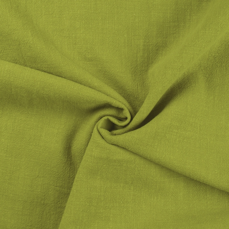 May include: A close-up of a soft, green fabric with a textured surface. The fabric is folded and draped, creating a smooth, flowing look.